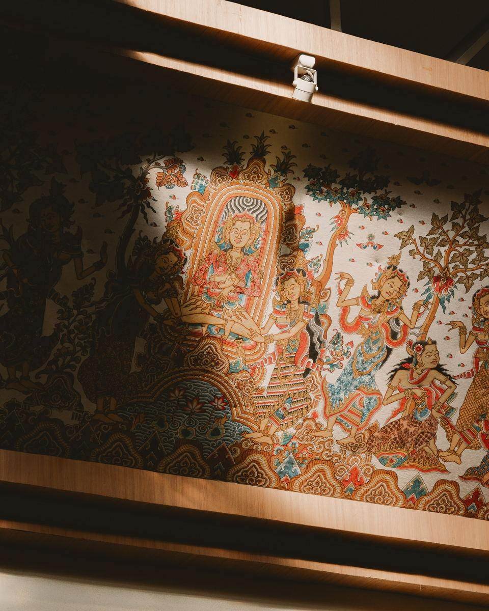 Balinese narrative painting lit through ceiling slats, half in shadow