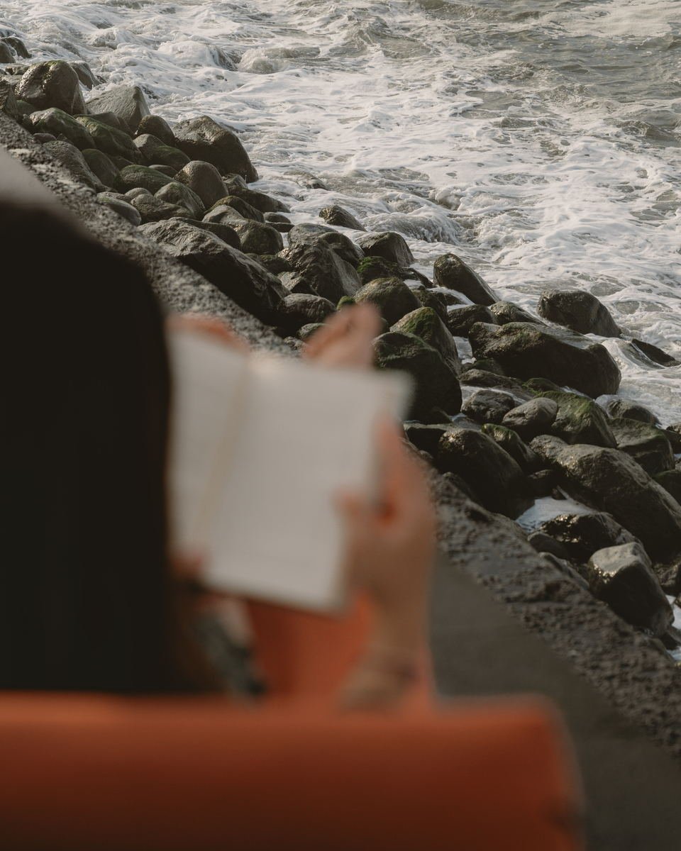 Open book held in the foreground, white water breaking over rocks behind