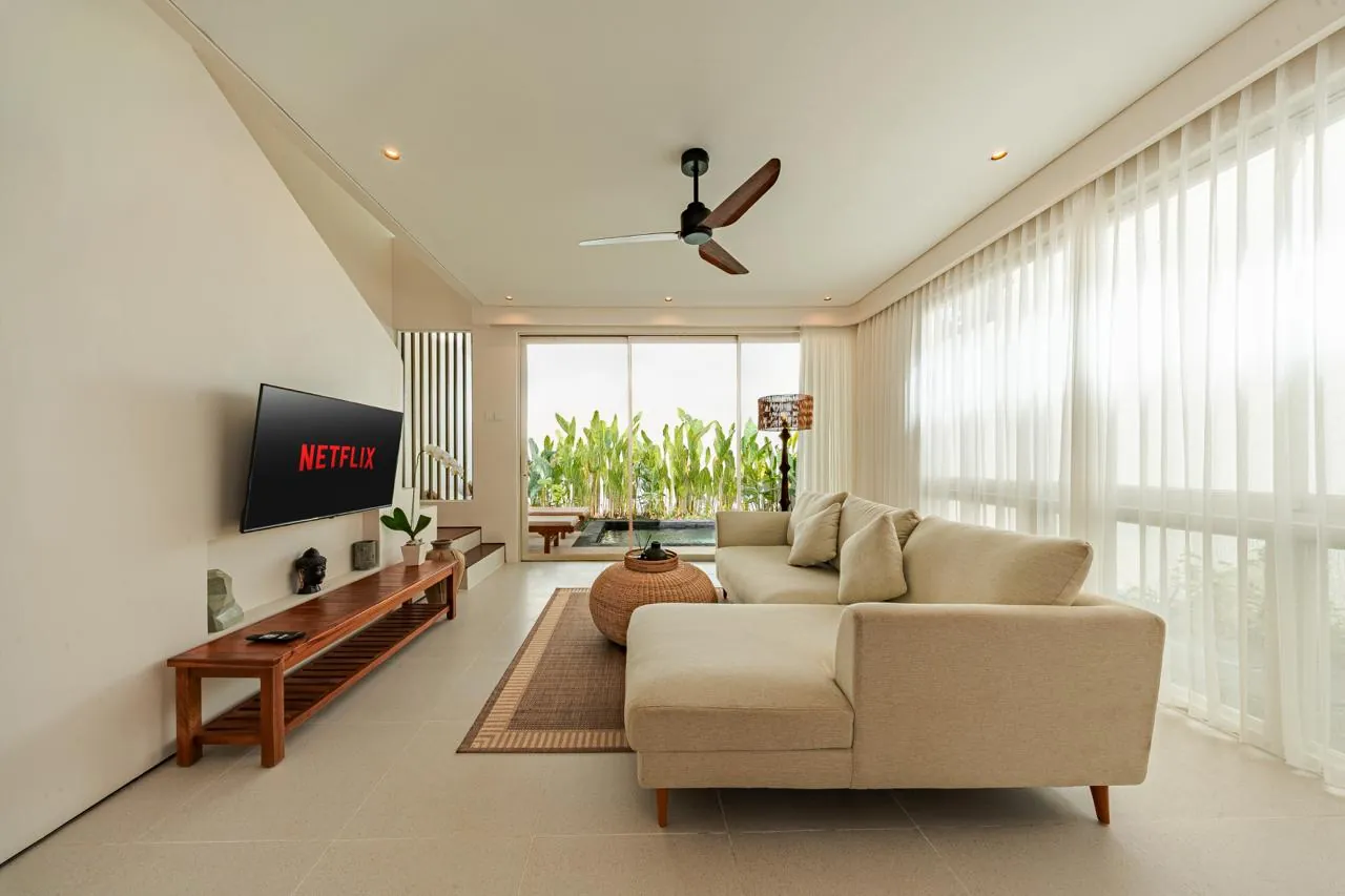 Bright living room with sheer curtains, a cream sofa and glass doors to a plunge pool