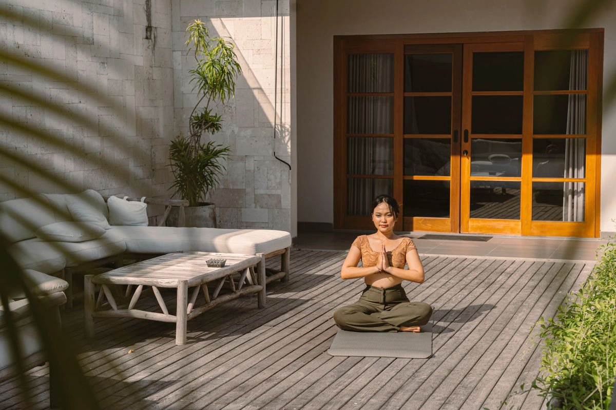 Guest seated on a mat in morning light on the timber deck at a Seminyak villa